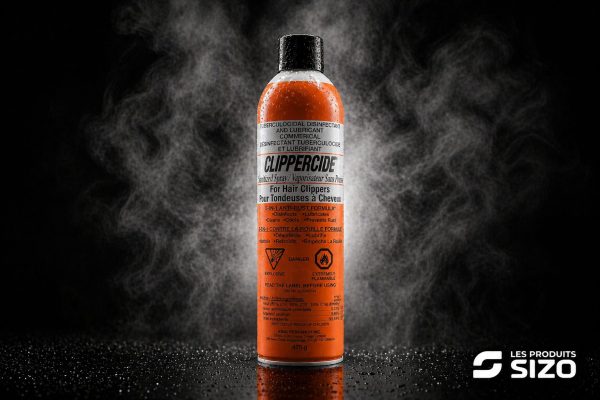 Orange ClipperCide disinfectant spray for hair clippers, black cap, on a reflective surface with a smoky dark background; brand logo bottom right.